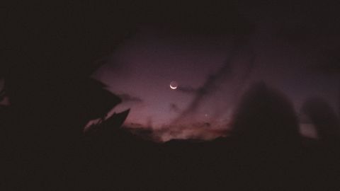 A captivating night sky featuring a crescent moon amidst silhouetted clouds.