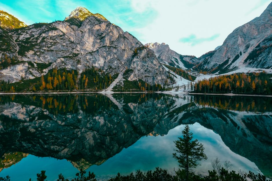 Breathtaking view of a serene lake reflecting majestic mountains and autumn foliage.