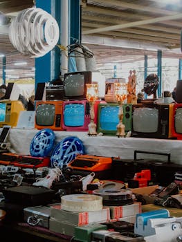Colorful vintage TVs and electronics displayed at a bustling flea market.