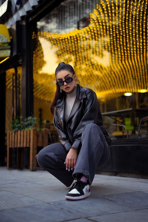 Free Fashionable woman crouching in urban environment with glowing neon lights. Stock Photo