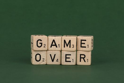 Wooden letter blocks forming the words 'Game Over' on a green background.
