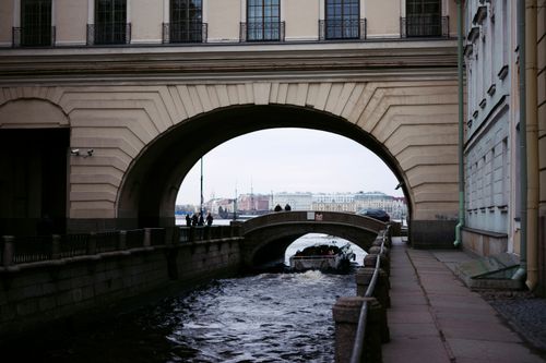 Free View of an arched bridge over a canal in St. Petersburg, Russia, with a boat passing underneath. Stock Photo