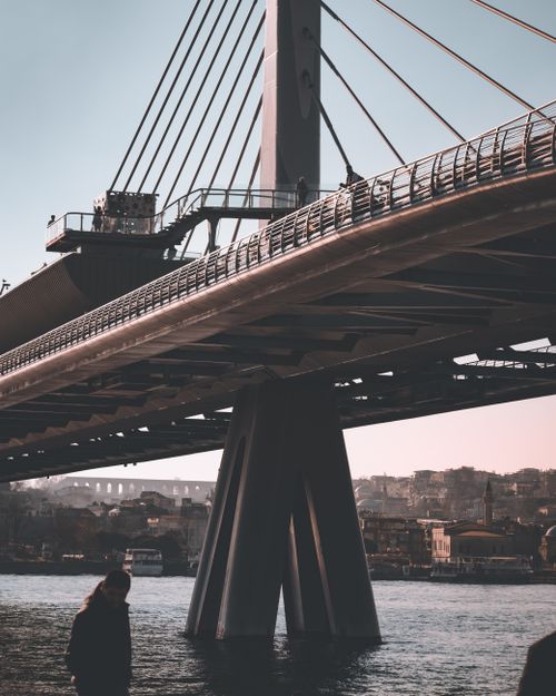 Free Dramatic view of a cable-stayed bridge over a city river during daytime with an urban skyline. Stock Photo