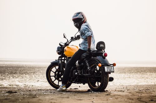 Free Man wearing helmet on Royal Enfield bike at the beach, exuding freedom and adventure. Stock Photo