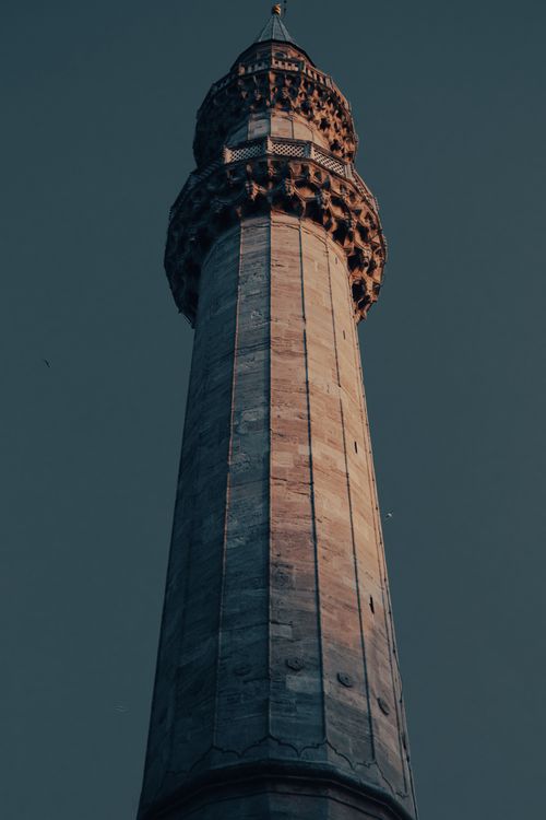 Free Low angle shot of a historic minaret tower under a blue sky, showcasing its intricate architecture. Stock Photo