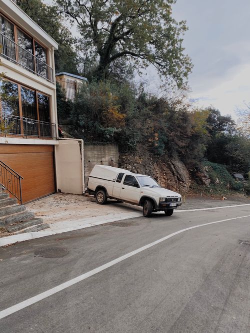 Free A white pickup truck parked on a scenic road in Montenegro, next to modern hillside homes. Stock Photo