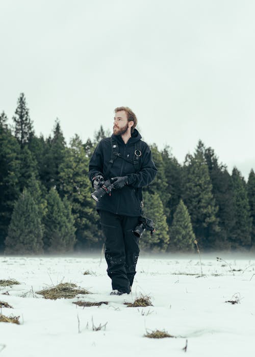 Man with Camera Walking in Winter Nature near Forest