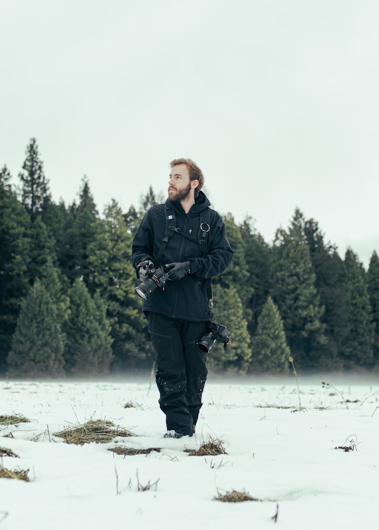 Man With Camera Walking In Winter Nature Near Forest