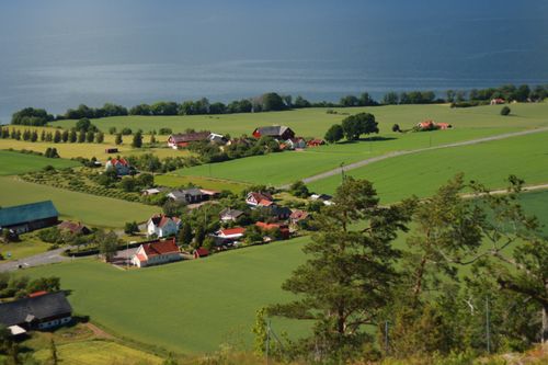 Free Aerial view of a picturesque village surrounded by lush fields and a serene lake, showcasing rural charm. Stock Photo