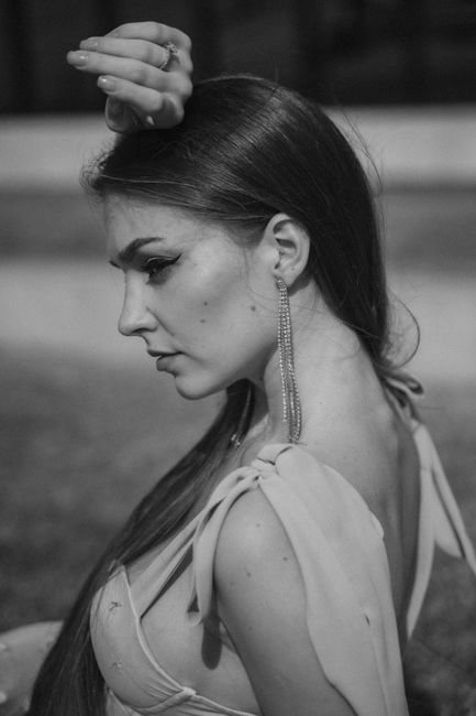 Stylish portrait of a woman in black and white with elegant earrings and dress.