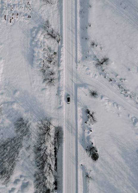 Drone view of a car driving on a snowy road in Hokkaido, Japan during winter.