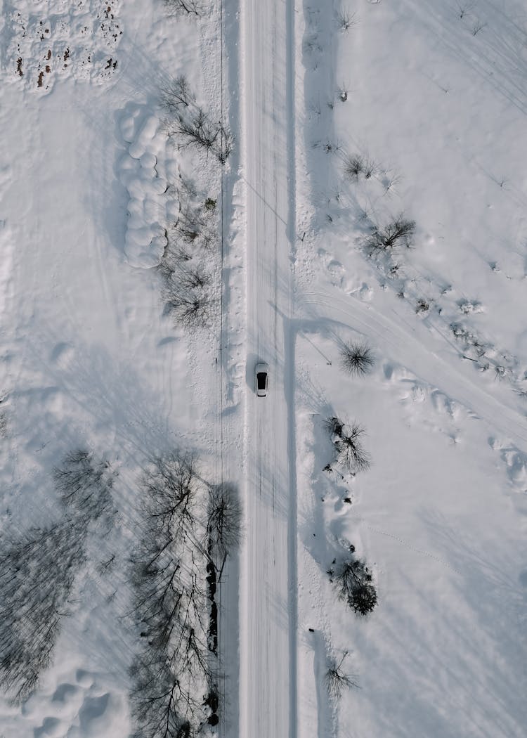 Aerial View Of Car Driving Along Snowy Road