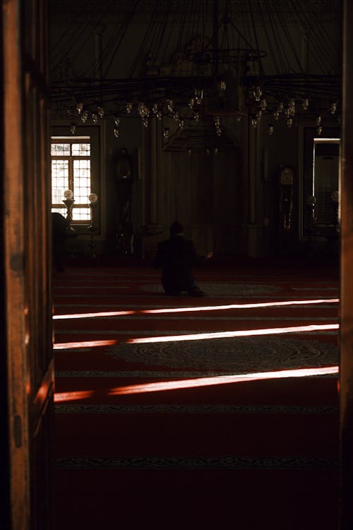 Photo of a Person Praying in a Dark Room