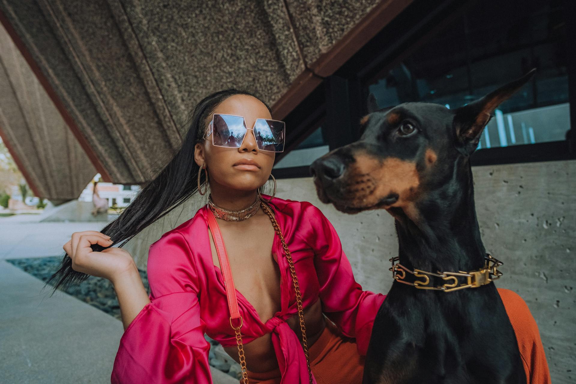 Photograph of a Woman with Sunglasses Posing with a Dobermann