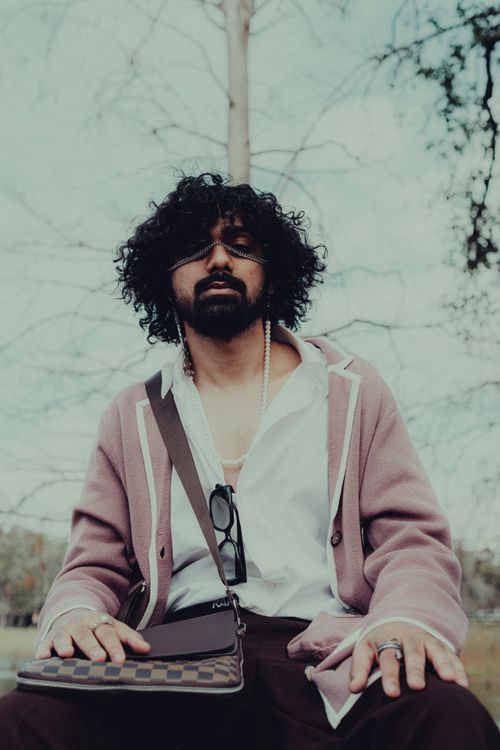 Free Fashionable man with curly hair and beard posing in park wearing pink jacket and accessories. Stock Photo