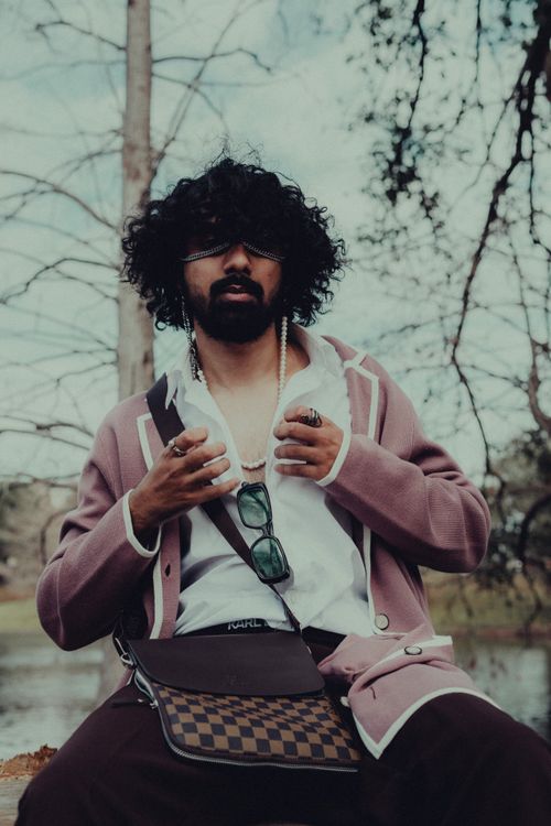 Free Fashionable man with curly hair and beard wearing a pink blazer in an outdoor setting with leafless trees. Stock Photo