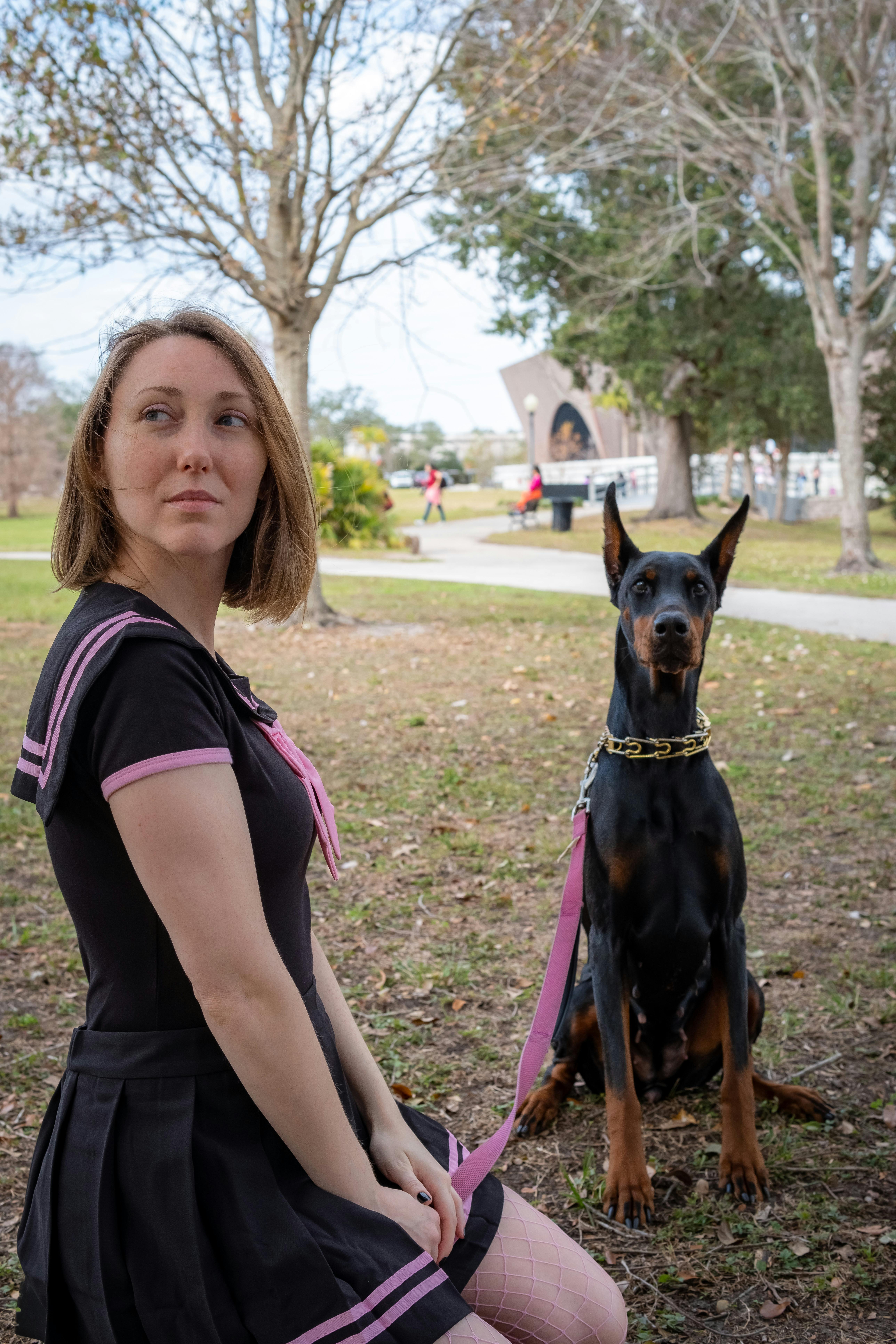 Free A woman and Doberman in a park, showcasing fashion and companionship. Stock Photo