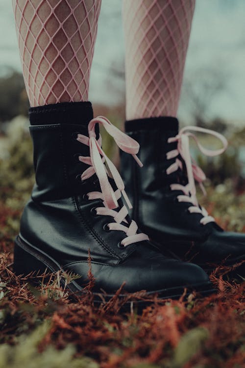 A Person Wearing Black Boots with Pink Lace