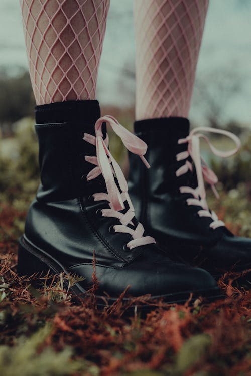 A Person Wearing Black Boots while Standing on Grassy Ground