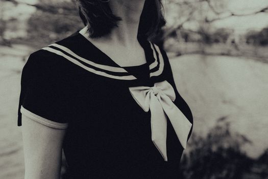 Elegant black and white portrait of a woman in a sailor blouse with striking bow detail.