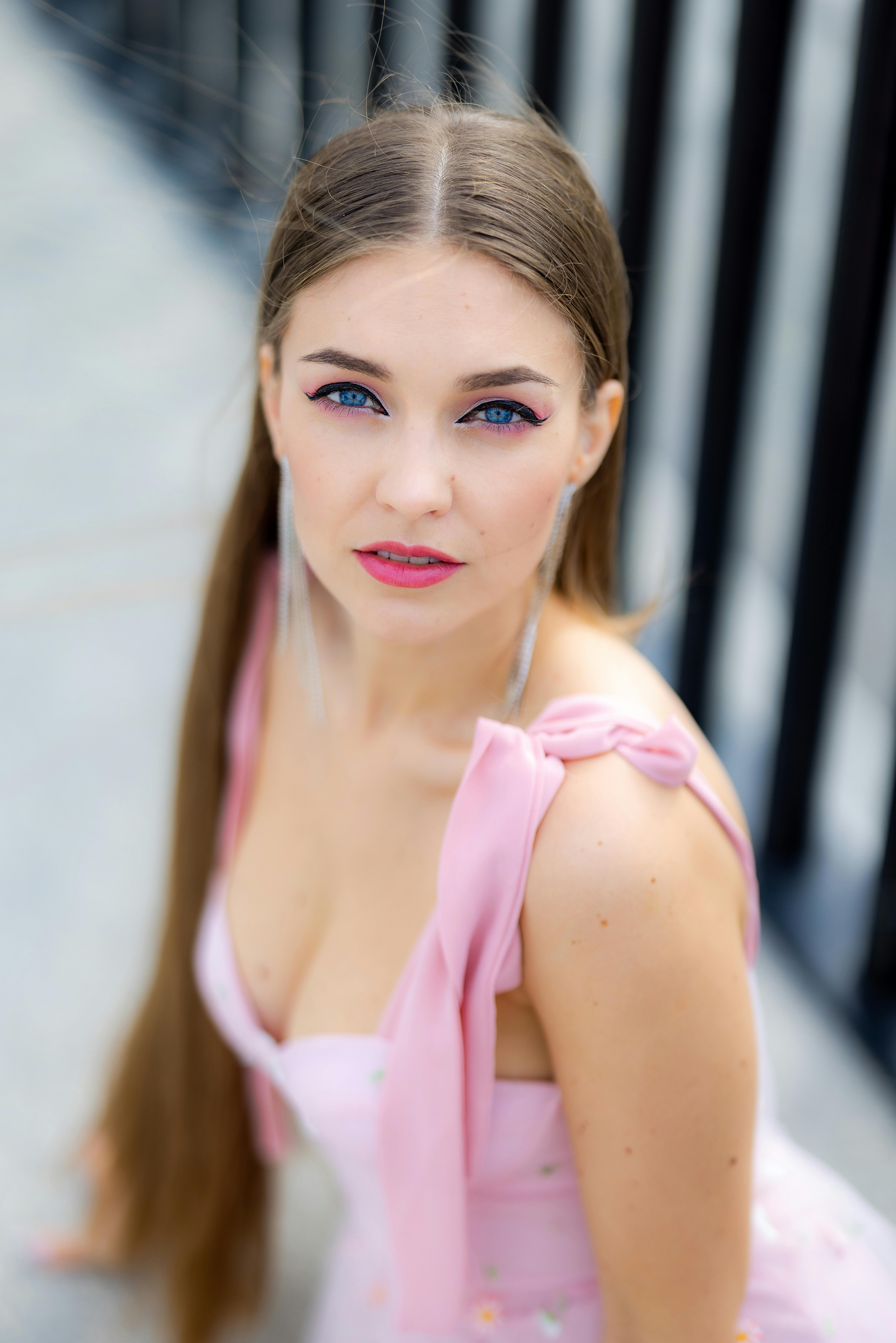 Portrait of a young woman with long hair and blue eyes in an elegant pink dress.