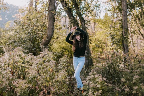 Woman Standing Beside Trees and Flower Field