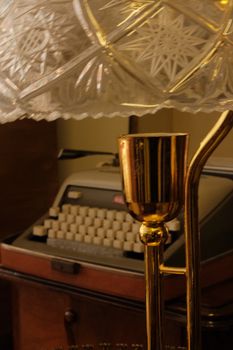 Antique typewriter with elegant crystal lamp, evoking nostalgia.