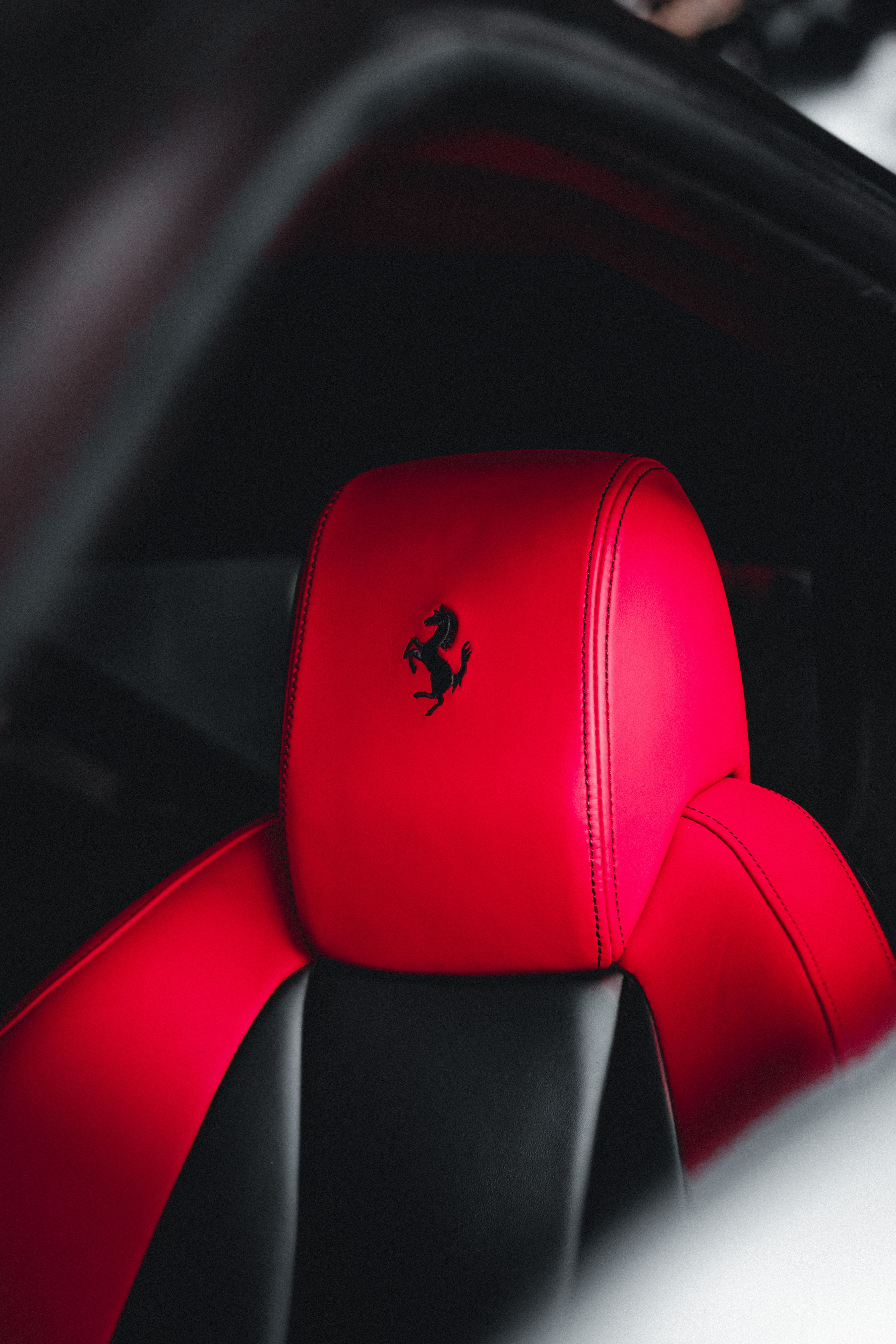 Close-up of a luxury car's vibrant red seat with a black logo symbolizing elegance and speed.