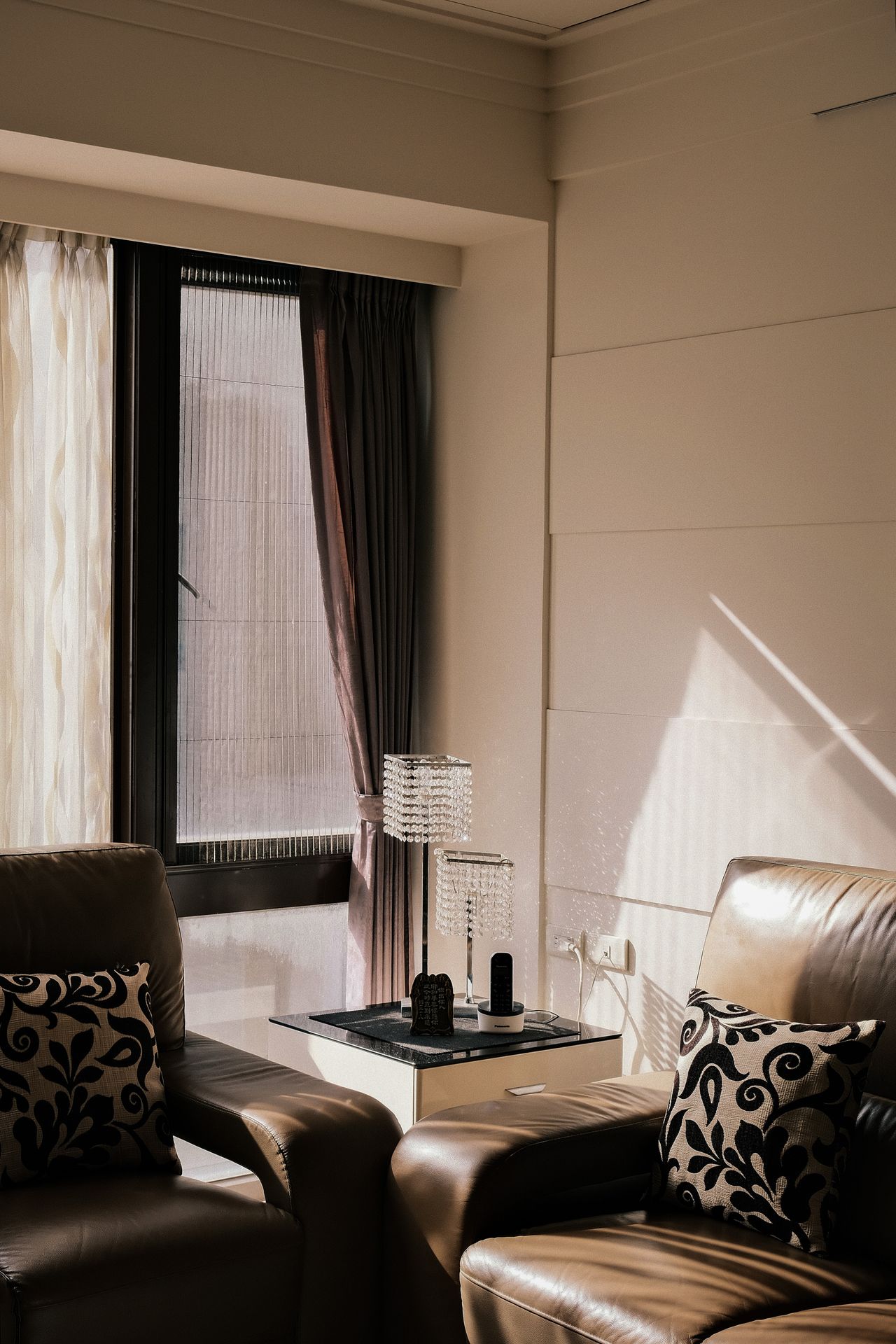 Pair of brown leather armchairs with patterned pillows flanking a table with crystal lamps