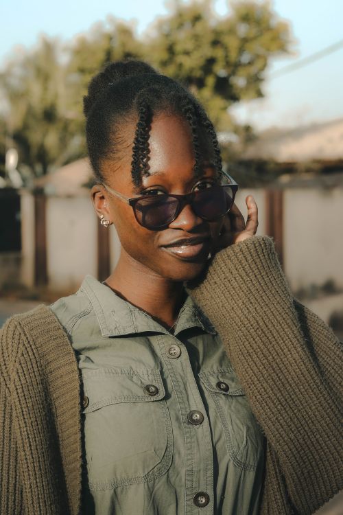 Free Fashionable woman posing outdoors in a green dress and sunglasses, showcasing urban style. Stock Photo