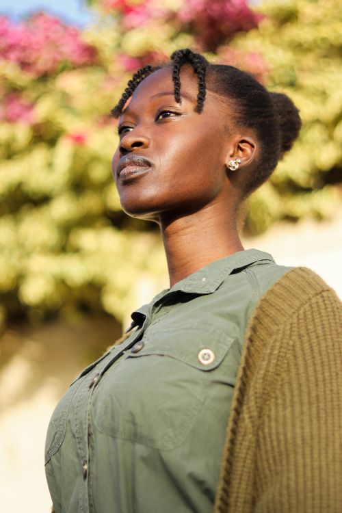 Free Portrait of a young woman in an outdoor setting, wearing a green outfit, showcasing modern fashion with a natural backdrop. Stock Photo