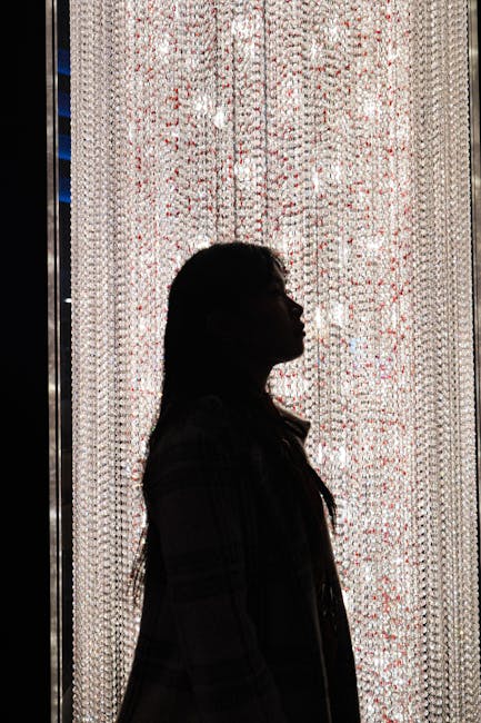 A woman's silhouette striking a pose in front of a luxurious illuminated crystal curtain, adding a touch of glamour.