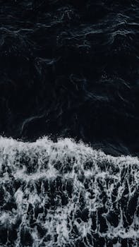 Beautiful waving sea splashing on shore with the Quote "Anger is an acid that can do more harm to the vessel in which it is stored than to anything on which it is poured." written on it and have average color value #272D33