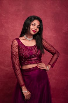Beautiful South Asian woman posing in traditional attire against a red background.
