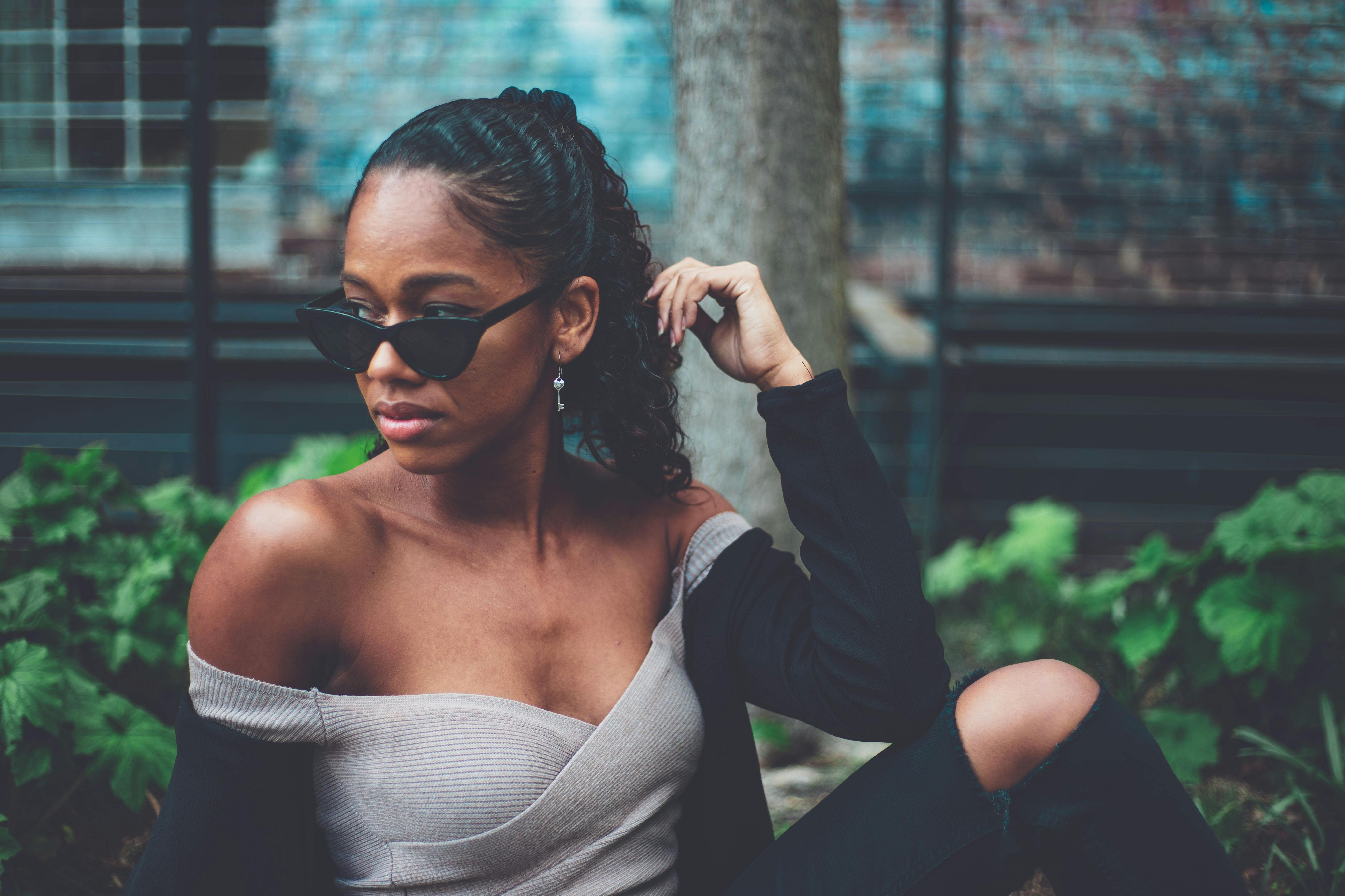 一位时尚女性戴着太阳镜在户外摆姿势的肖像，呈现休闲时尚的外观