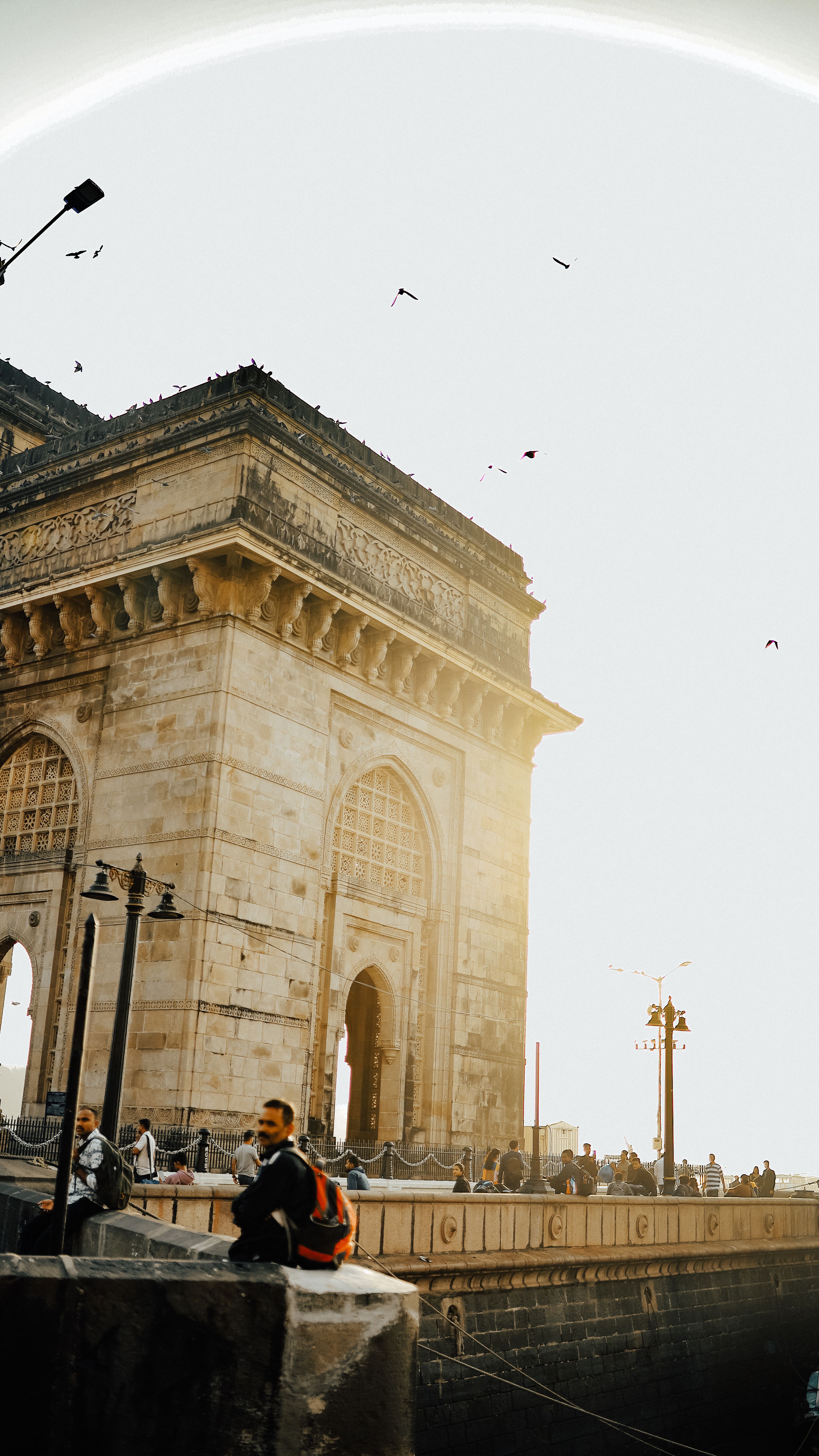 Iconic view of the Gateway of India with people around during sunset in Mumbai, India.