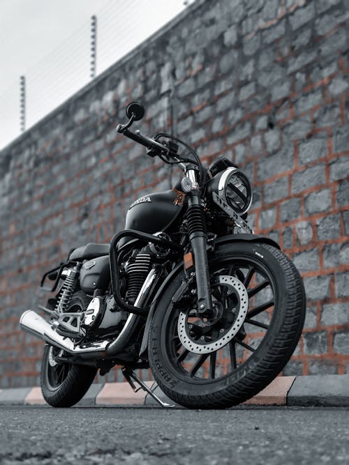 Black Motorcycle Parked near a Stone Wall