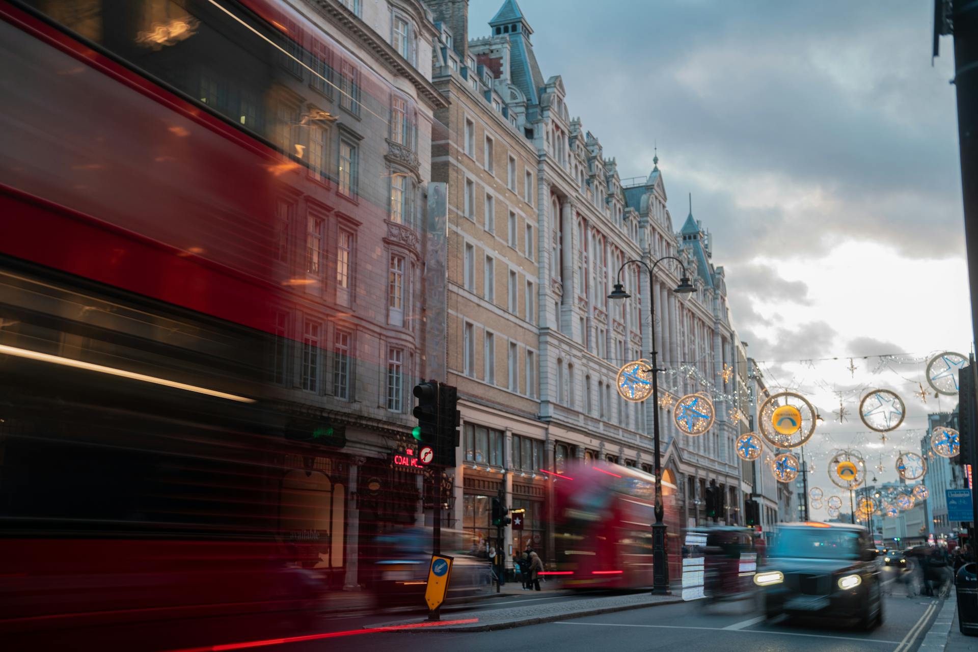 A vibrant London street scene with motion blur capturing red buses at dusk.