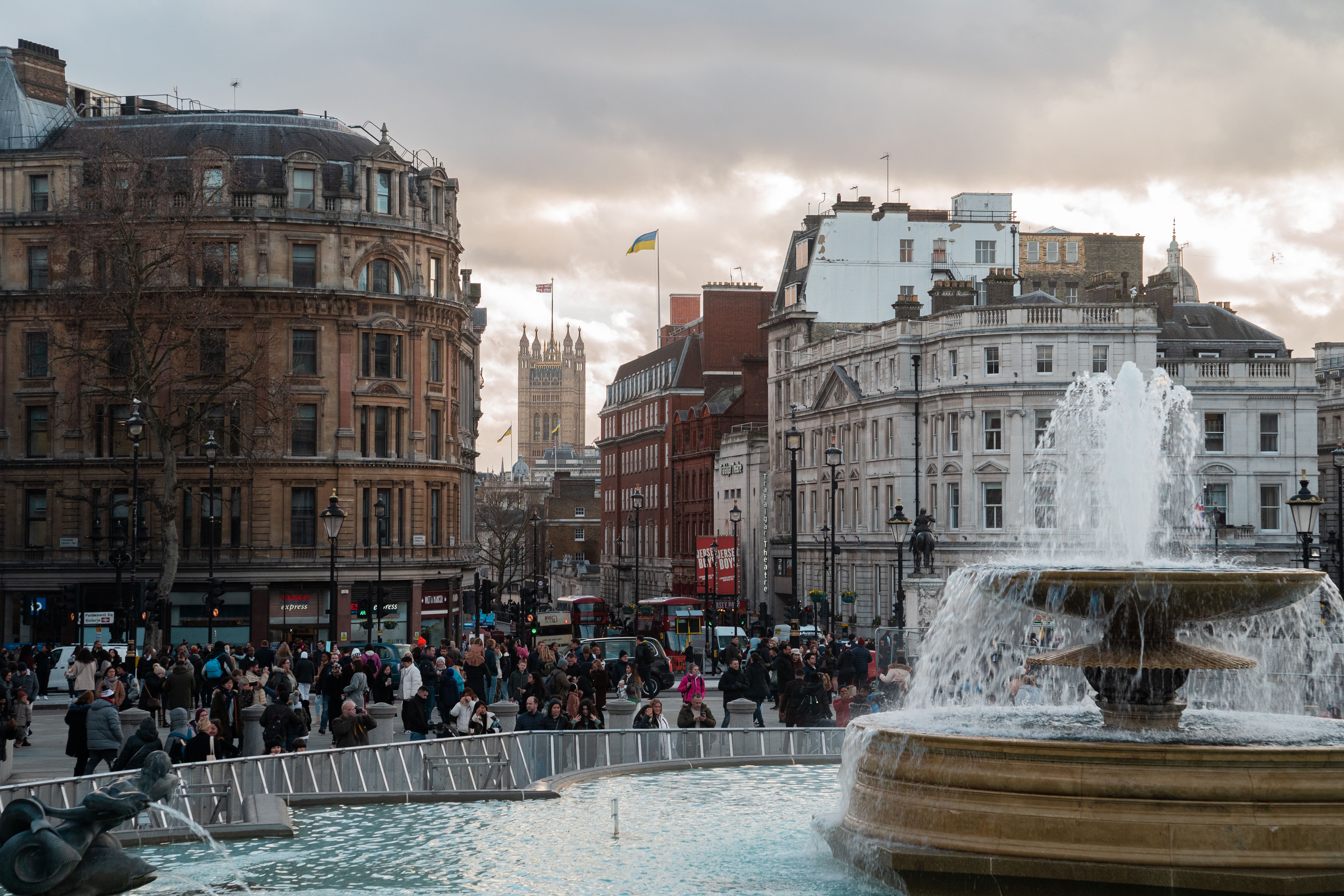 Lively scene at Trafalgar Square, London, featuring a bustling crowd and iconic fountain.