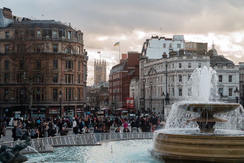 Lively scene at Trafalgar Square, London, featuring a bustling crowd and iconic fountain.