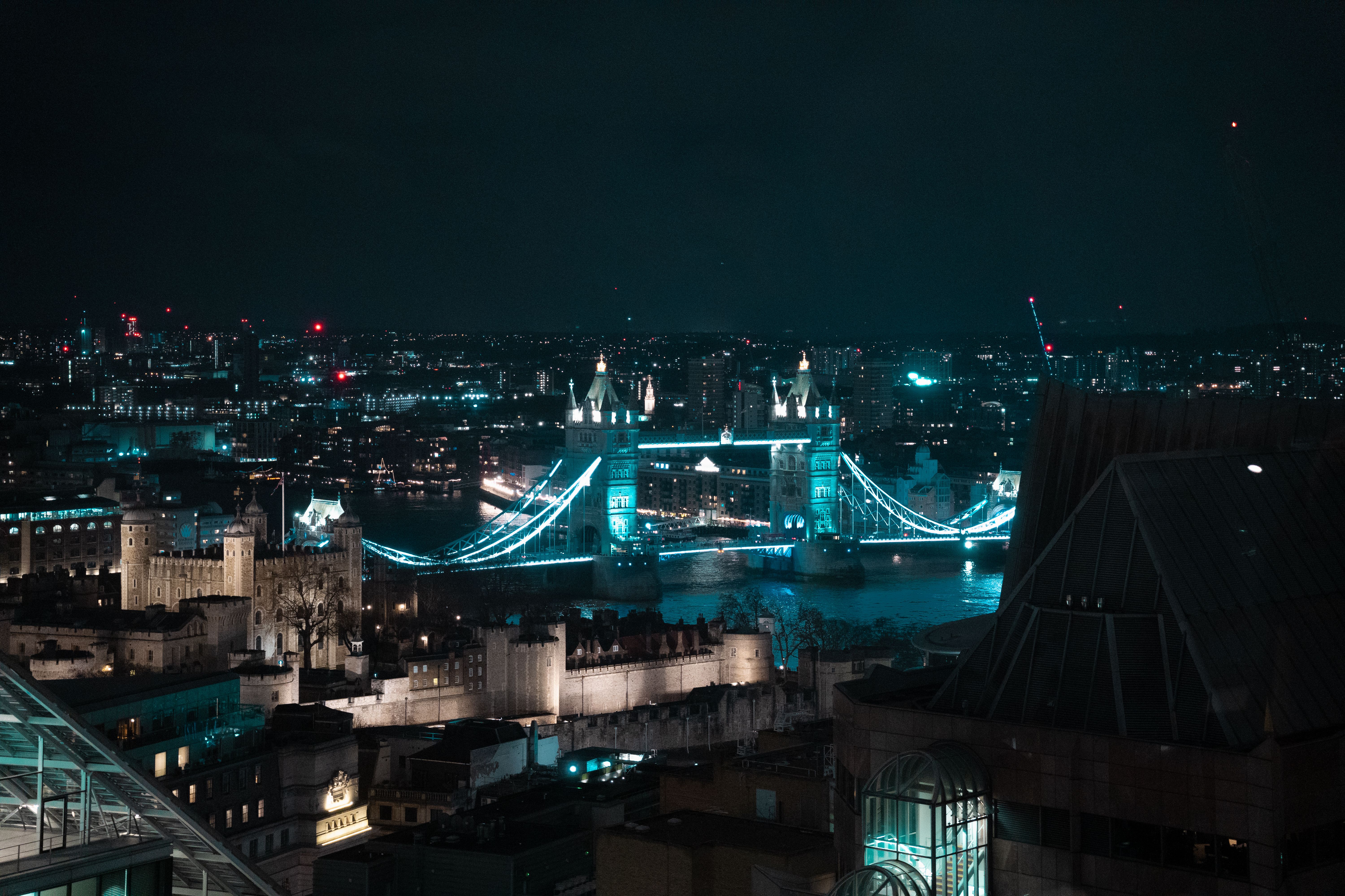 Stunning aerial shot of London's Tower Bridge lit up at night, reflecting on the River Thames.
