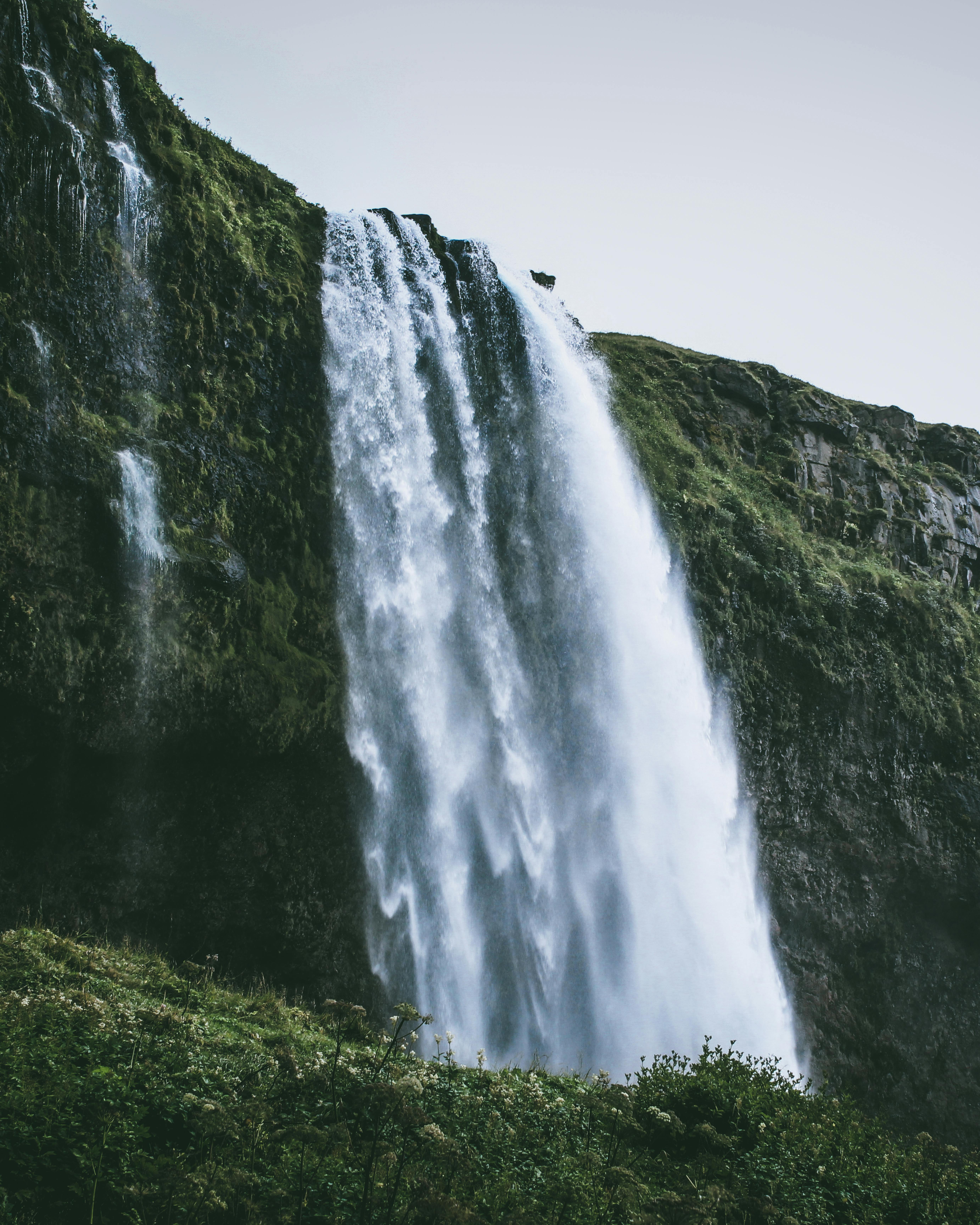 Stunning waterfall in Reykjavík, Iceland cascading over green mossy cliffs. Perfect for nature and travel visuals.