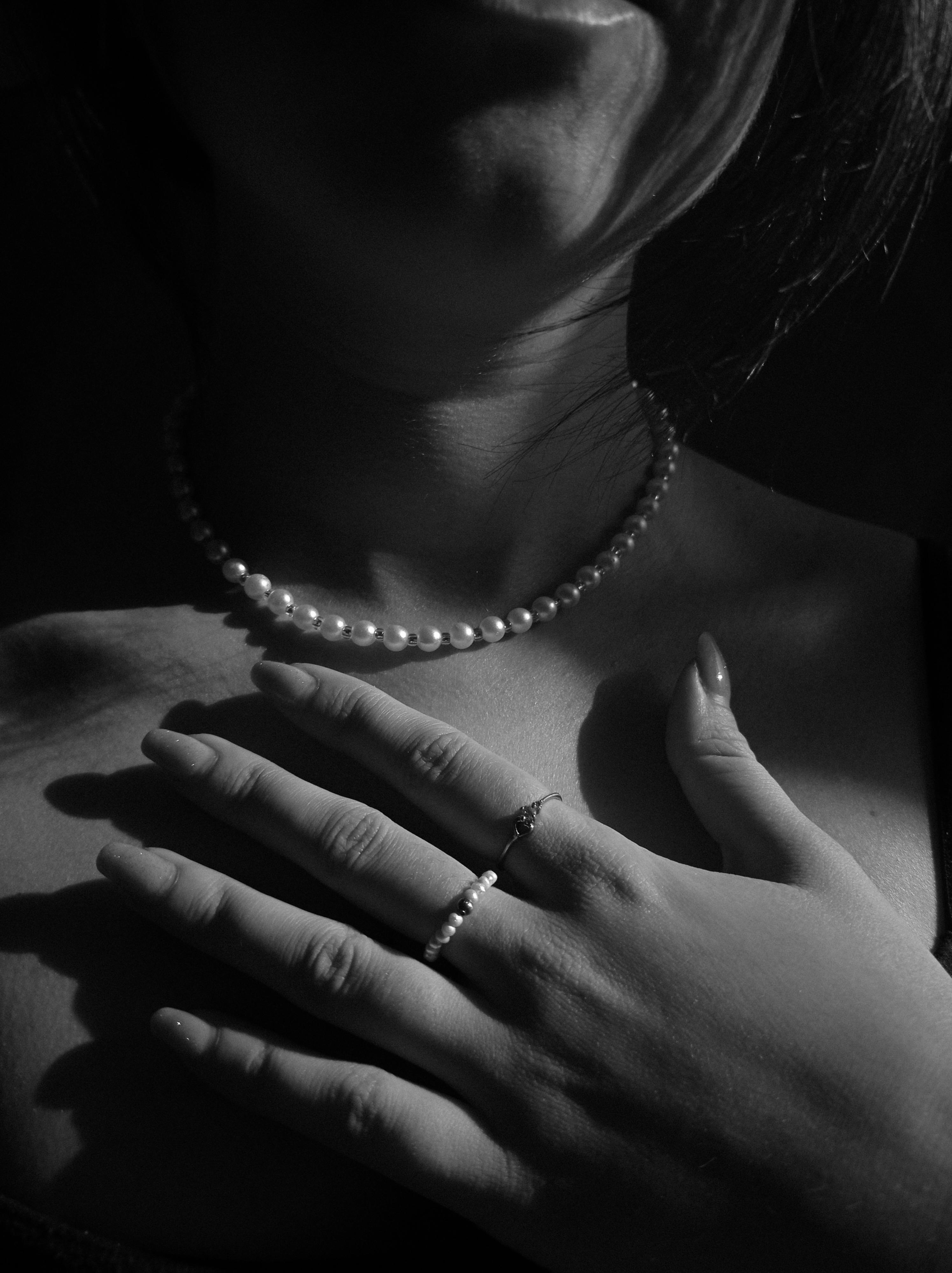 Close-up portrait featuring pearl necklace in dramatic black and white tones.