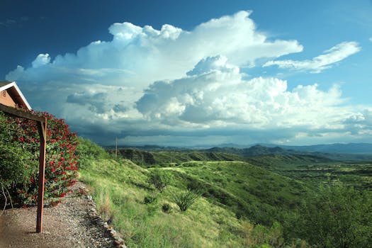 Beautiful rural landscape with hills, dramatic clouds, and greenery under a bright sky.