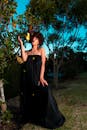 一位时尚女士身穿黑色礼服，在充满活力的花园中自信摆姿，捕捉到优雅与自然之美的融合