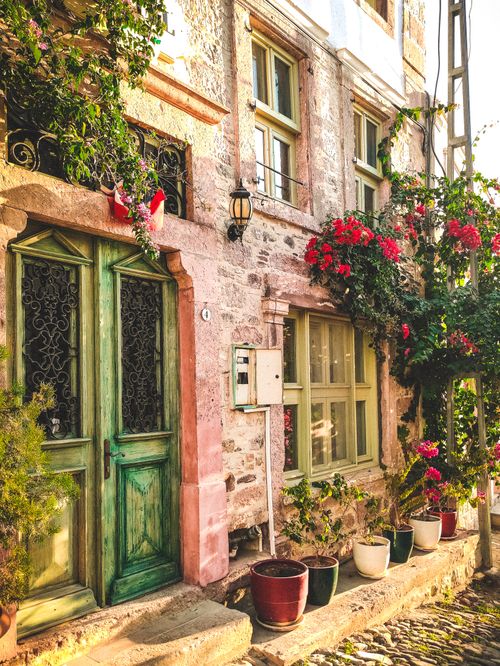 Free A picturesque street in Ayvalık, Türkiye featuring colorful flowers and historic architecture. Stock Photo