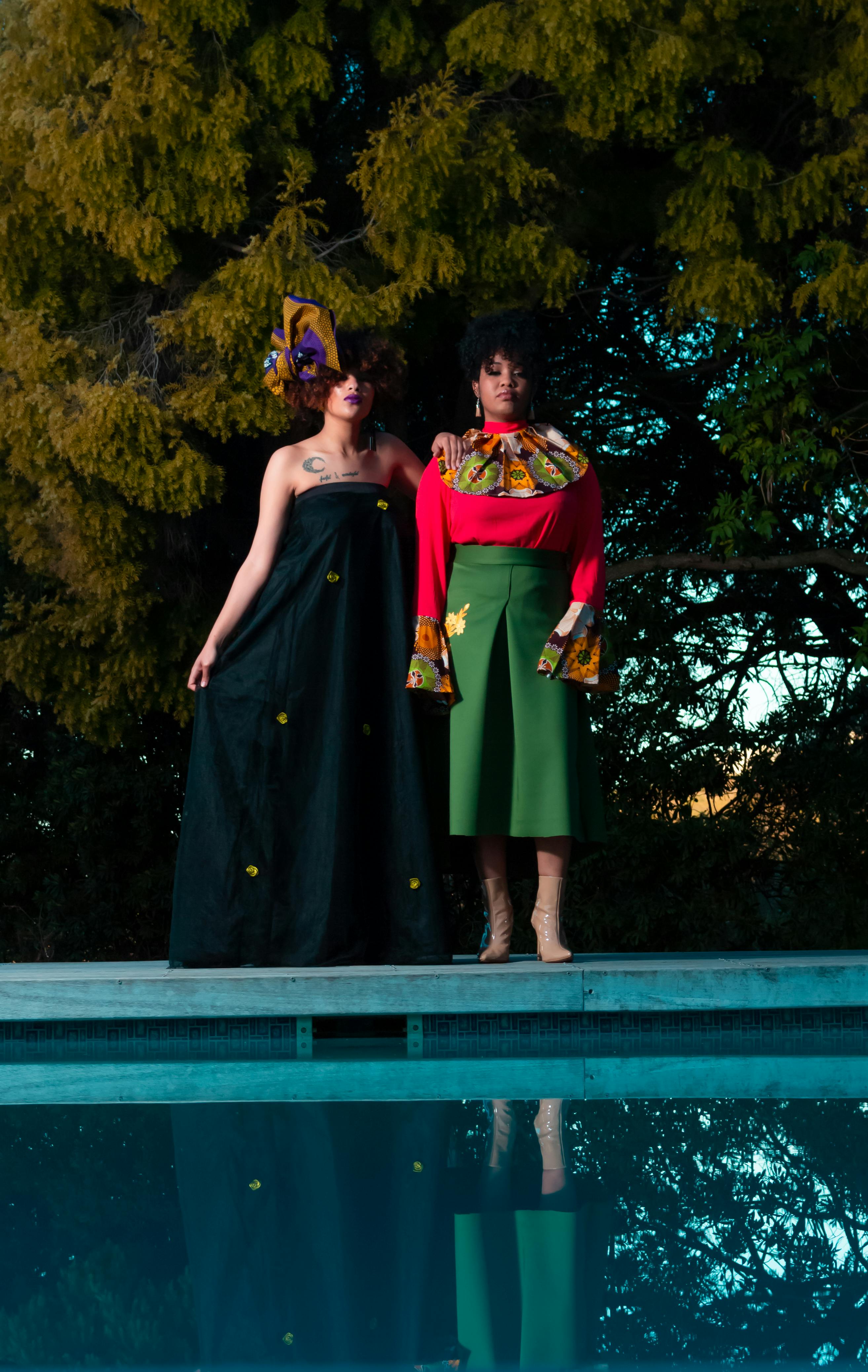 two woman standing in front of body of water