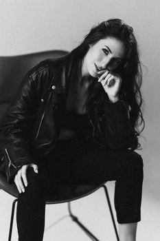 Black and white portrait of a woman sitting and smiling in a leather jacket.