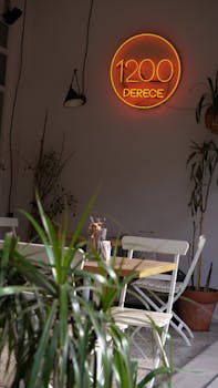 Stylish café interior featuring a glowing neon sign amidst lush indoor plants, perfect for design inspiration.