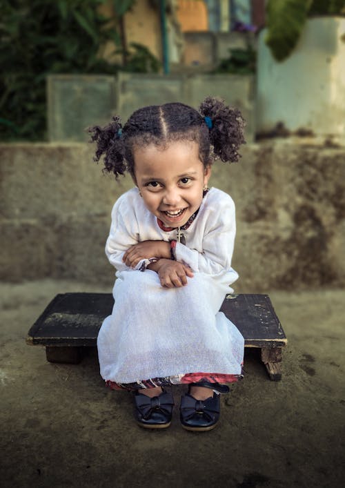 Little Girl in a White Dress Sitting and Smiling